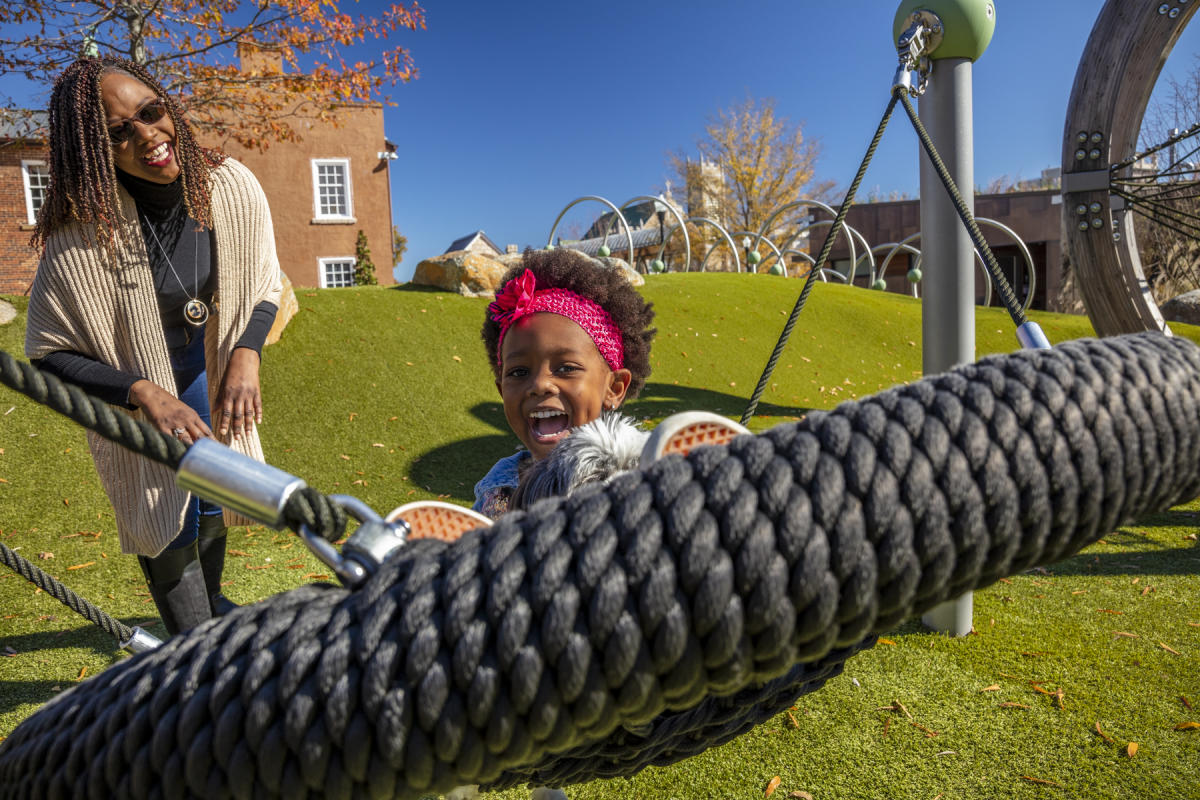 Mom pushing daughter on swing at park