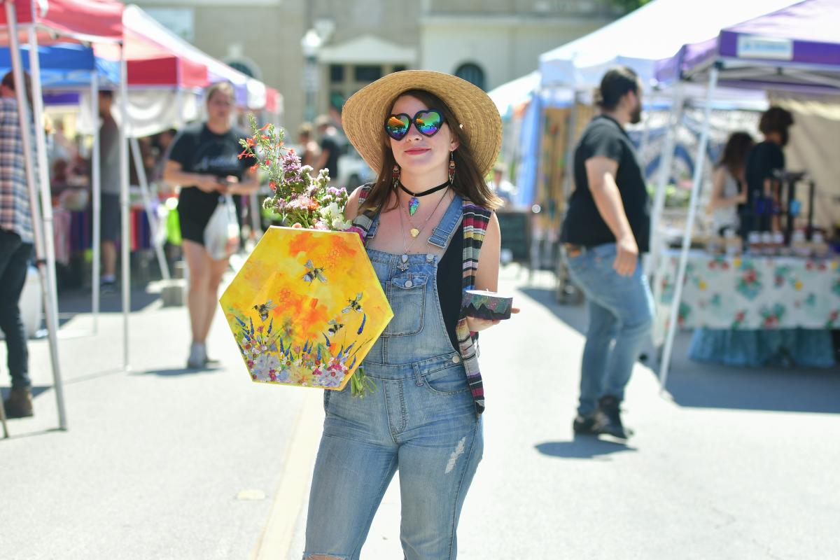 Woman holding up her finds at Art Squared and the Farmers Market in Downtown San Marcos