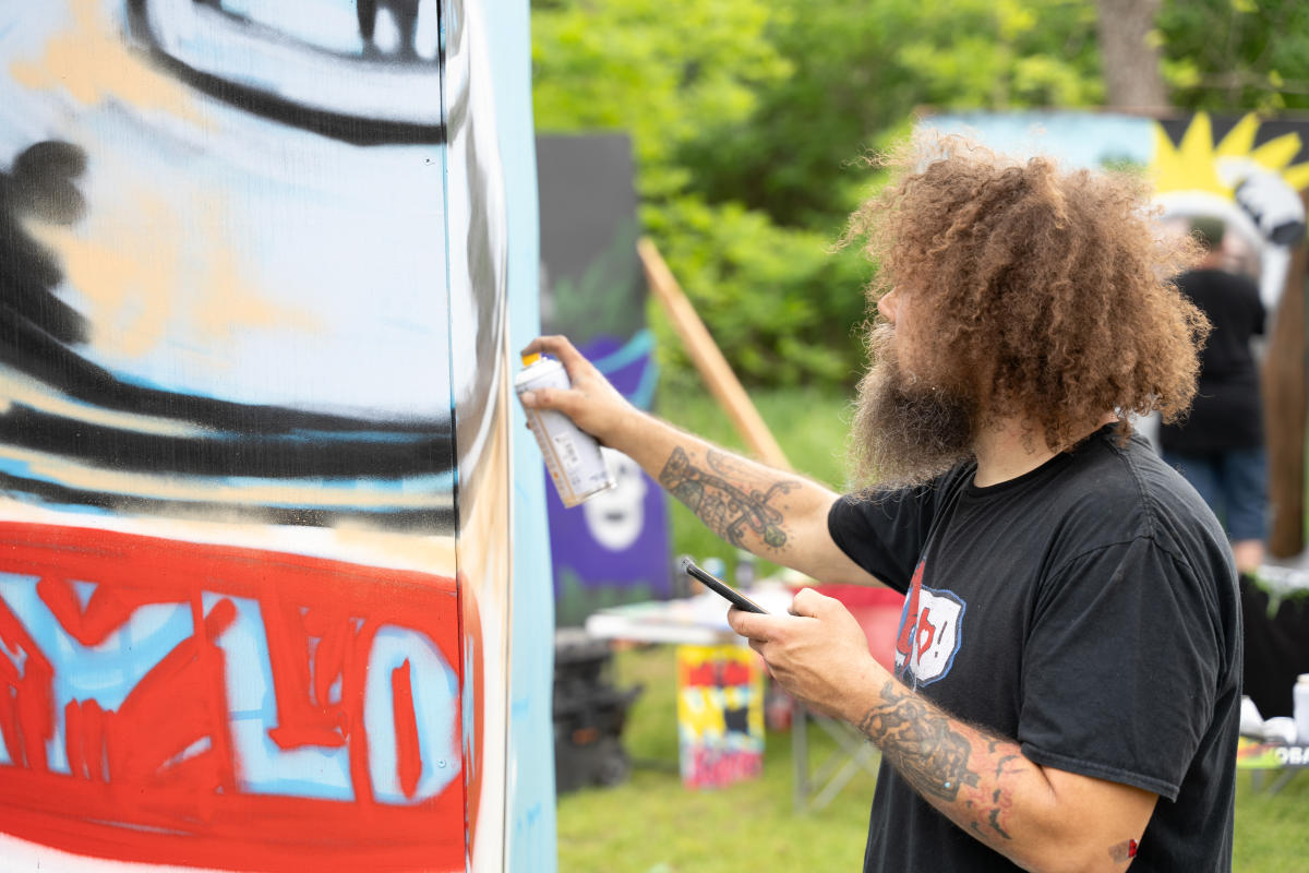 A man works on a mural at the San Marcos Studio Tour