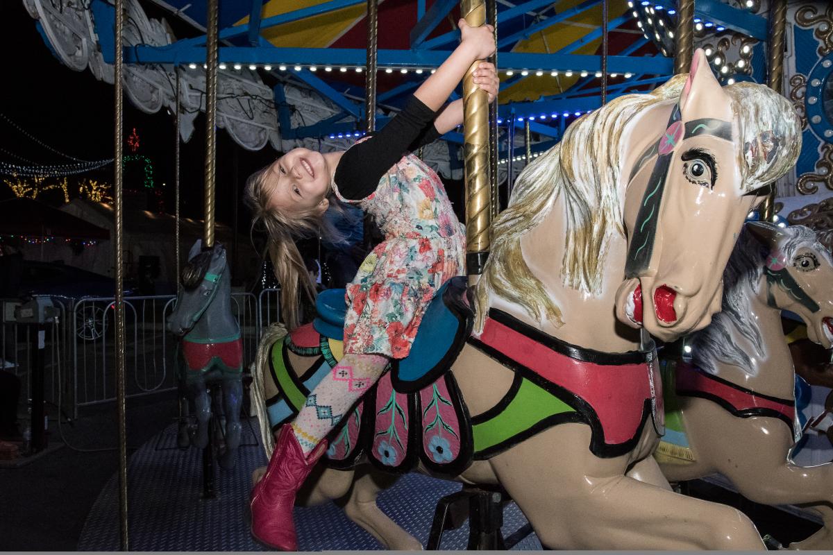 A little girl rides on a horse on the merry go round at Sights & Sounds of Christmas in San Marcos Plaza Park in San Marcos, Texas.