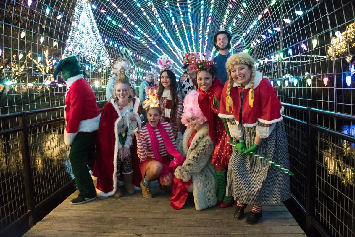 A group of people dressed up in their Christmas outfits pose under the Christmas lights over the San Marcos River at Sights & Sounds of Christmas. Sights & Sounds of Christmas is an annual holiday festival in San Marcos Plaza Park in San Marcos, Texas.