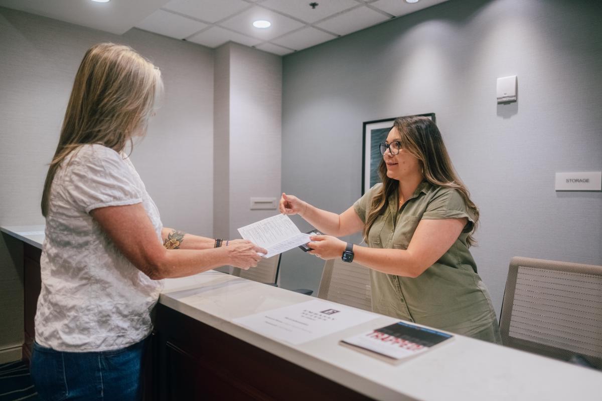 A woman helps a conference attendee find her way at the registration desk at the Embassy Suites Hotel & Conference Center in San Marcos, Texas.
