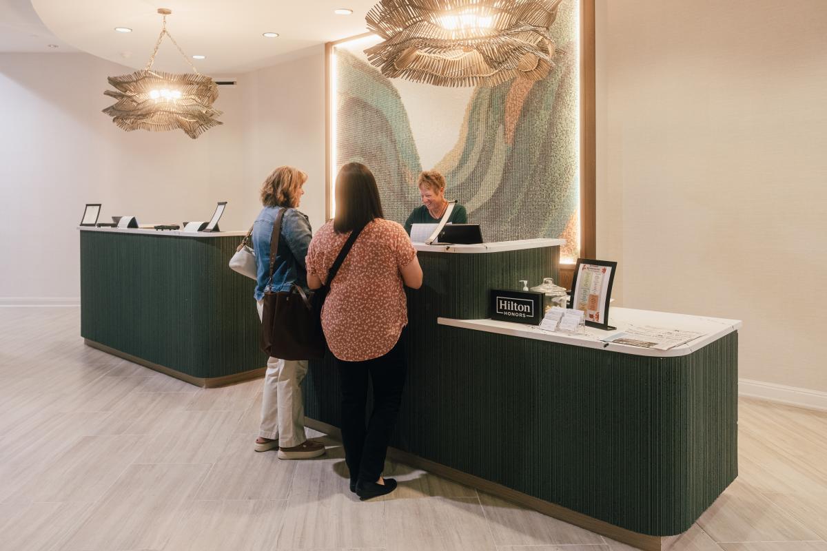 Two women check in to the Embassy Suites by Hilton San Marcos Hotel & Conference Center's front desk while visiting San Marcos, Texas.