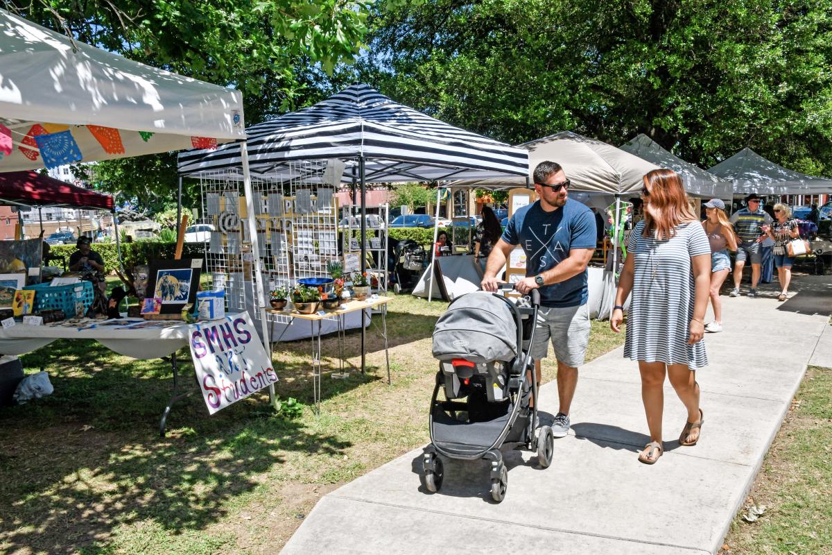 Family strolling through a pop-up art market in Downtown San Marcos, TX