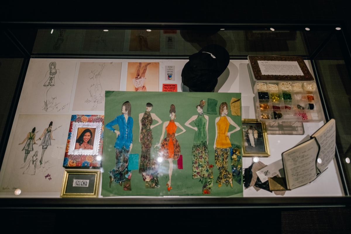 A glimpse at the fashion design display case at The Selena Effect at The Wittliff Collections at Texas State University. The display includes design sketches, materials, photos, and fabric samples.