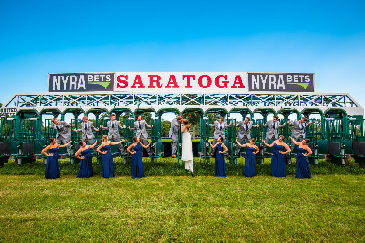Bride, Groom, and Bridal Party posing for a picture on the Saratoga Race track's starting gates
