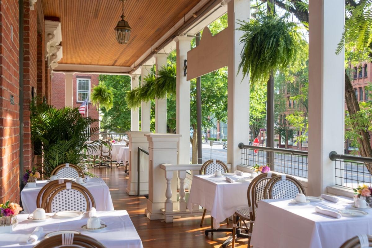 Looking down the length of the porch, tables with white tablecloths, hanging ferns