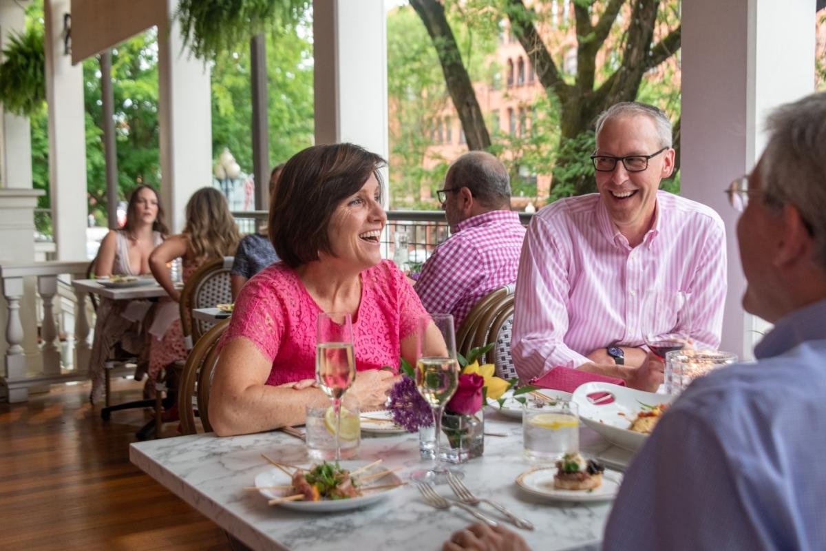 People enjoying dinner and laughing on the porch.