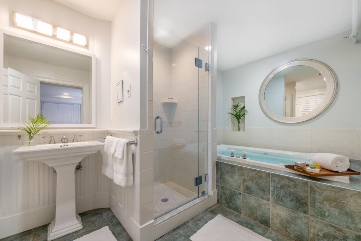 White bathroom with white pedestal sink and large marble tub