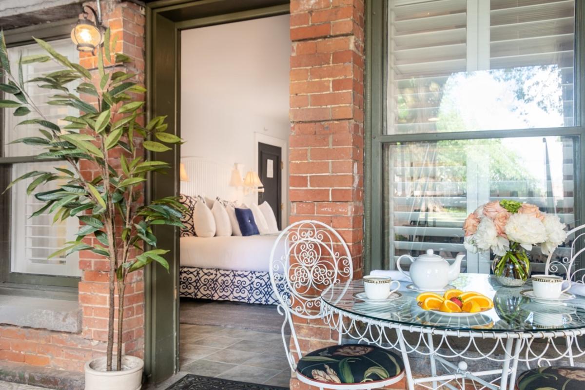 Looking in from front porch to guest room, wicker and glass table and chair on porch