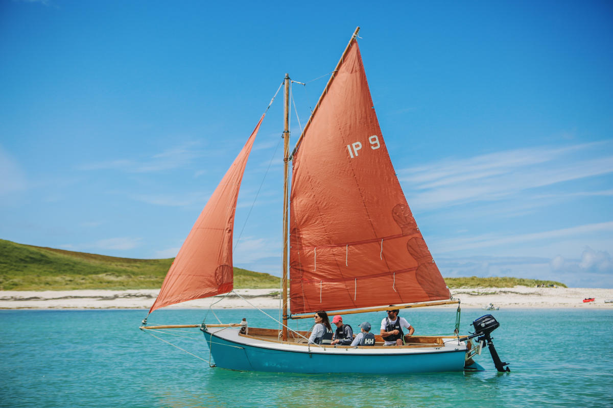 Family on a sailboat with red sail
