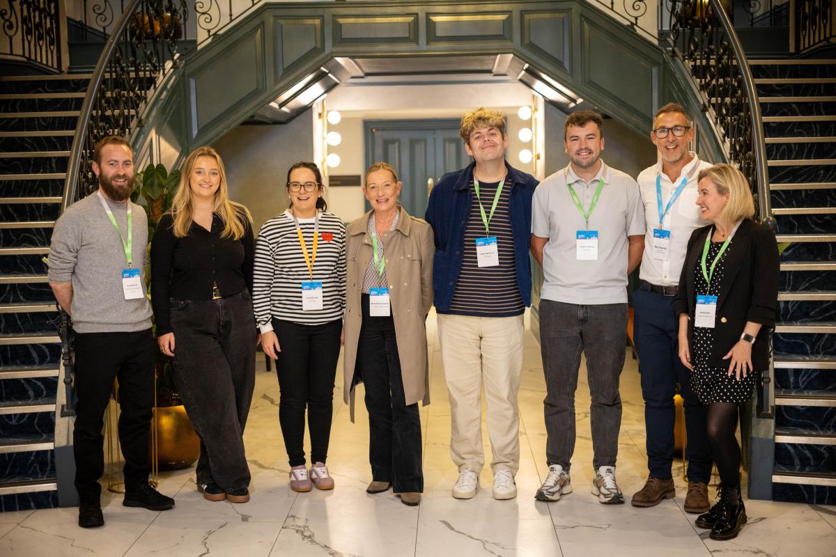 Attendees of an EMA Summit pose for a group photo alongside two staircases.