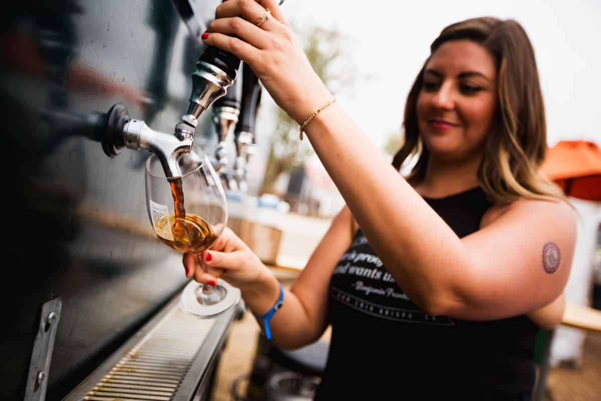 A woman pouring beer from a tap into a glass at SLO Cal bar
