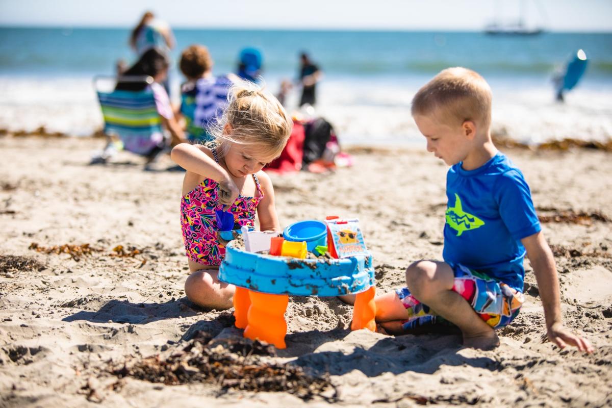 two kids playing in the sand at the beach