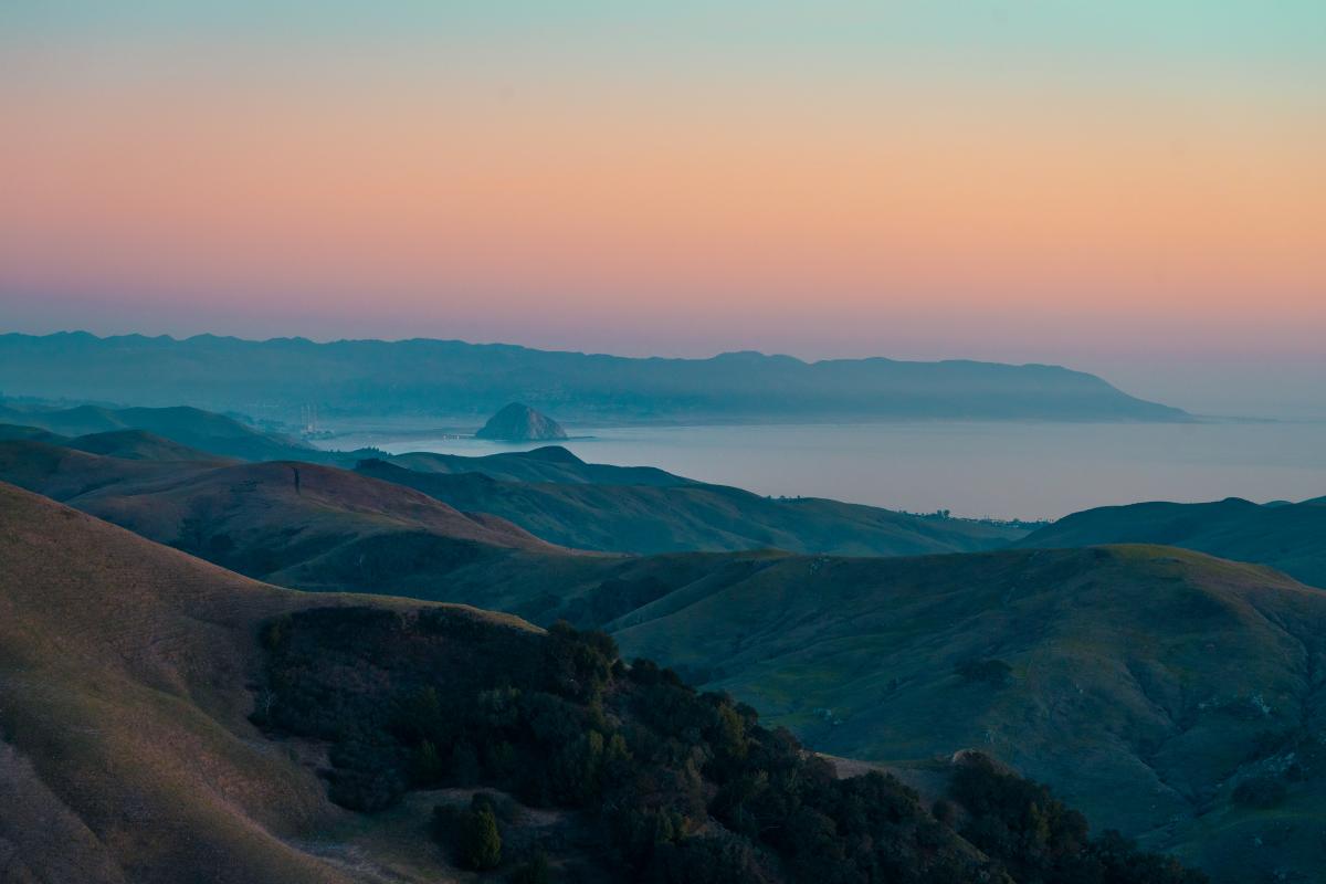 View of hills, ocean, and Morro Rock at sunset