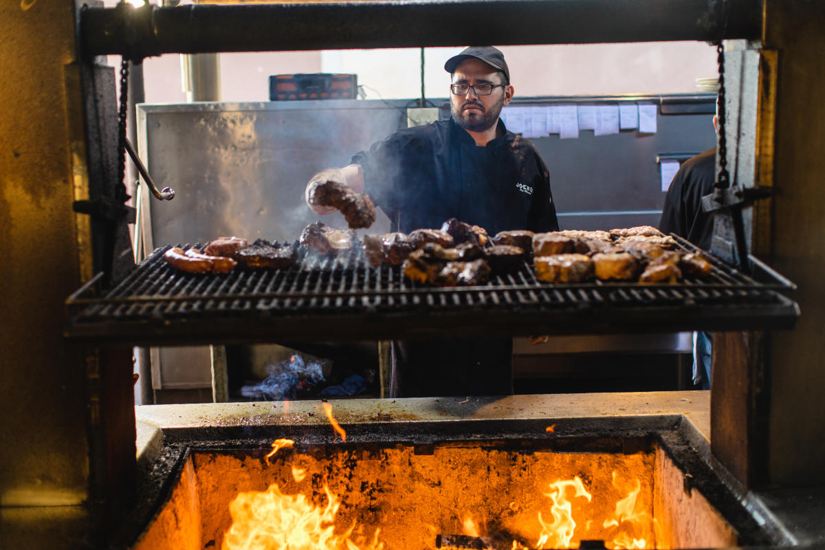 chef cooking steaks on wood-fired grill at Jocko's Steakhouse