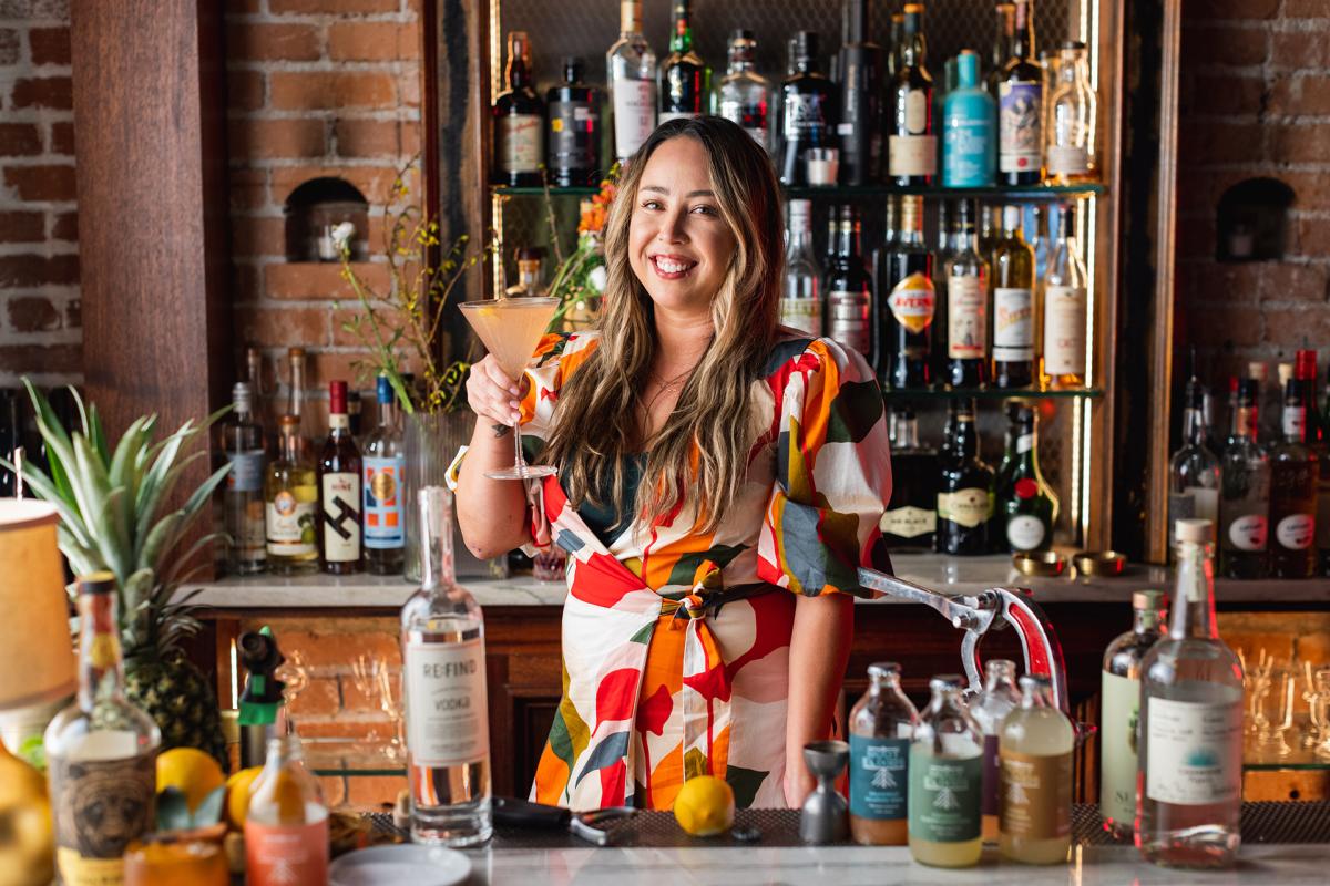 Female mixologist holding up drink behind the bar