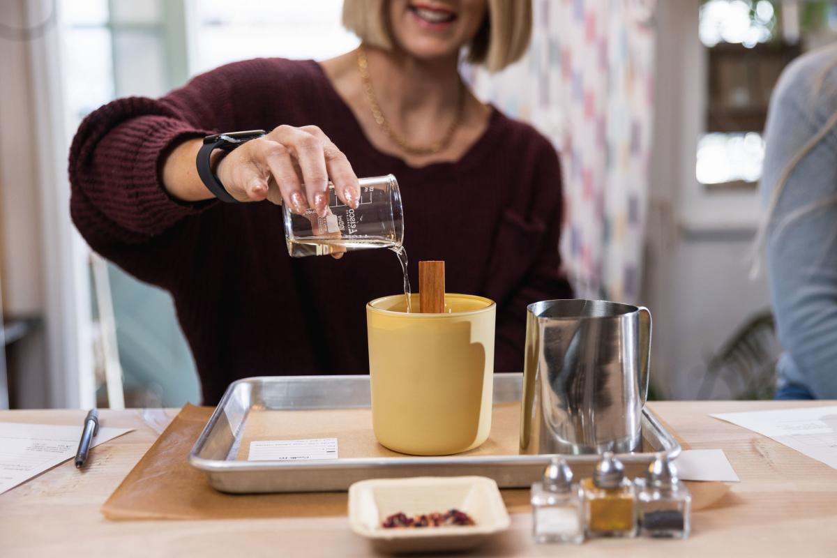 Women pouring oil into candle vessel