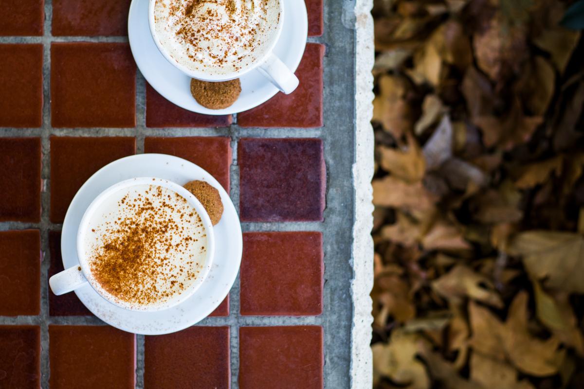 Two cups of coffee on table top with fall leaves