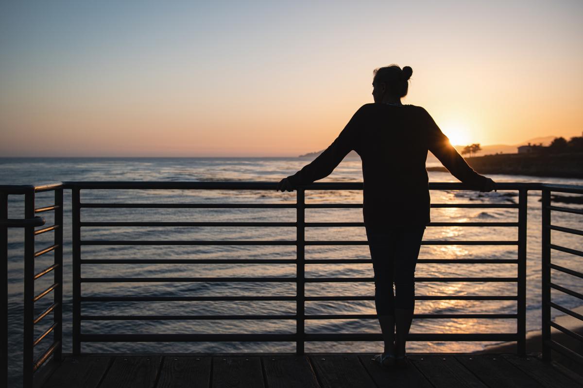 Person standing and looking out into the ocean at sunset in Pismo Beach, SLO CAL