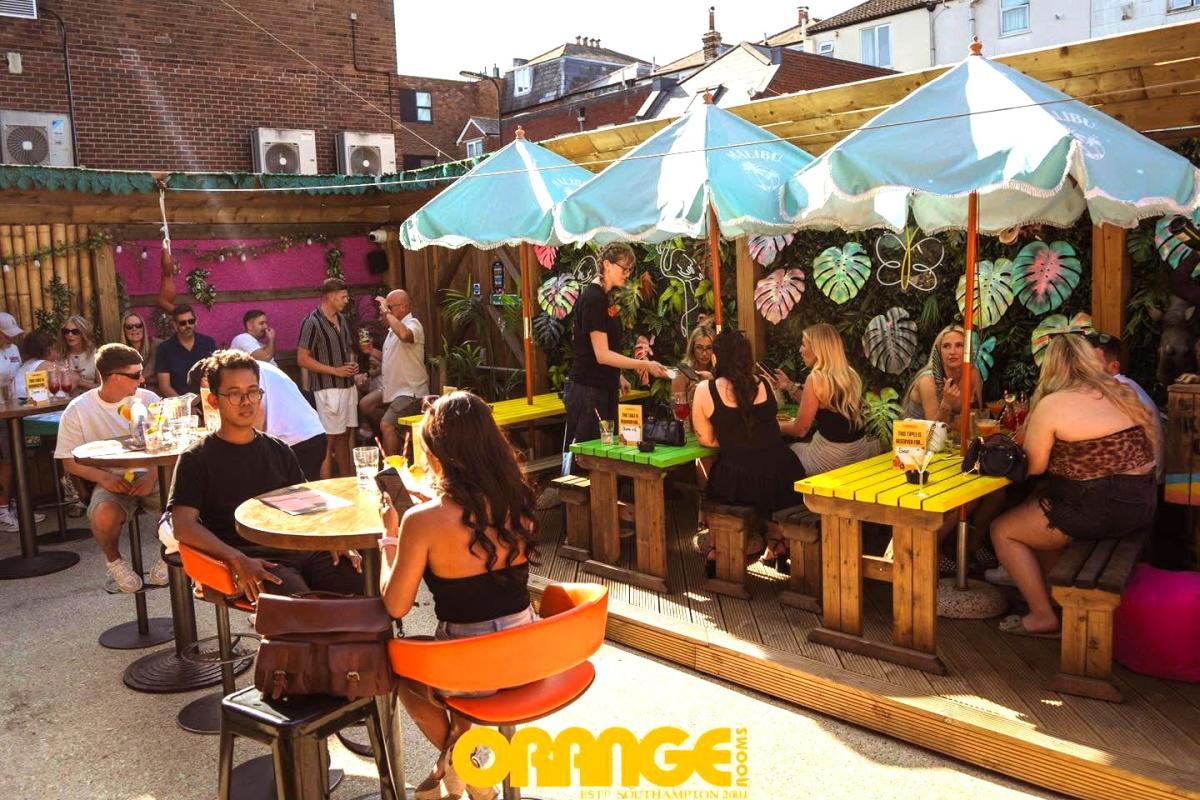 People enjoying drinks outside in Orange Rooms' Jungle Garden