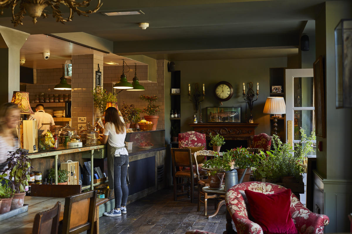 Rustic foyer of The Pig in the wall bistro with red armchairs, green plants and candle sticks on the walls