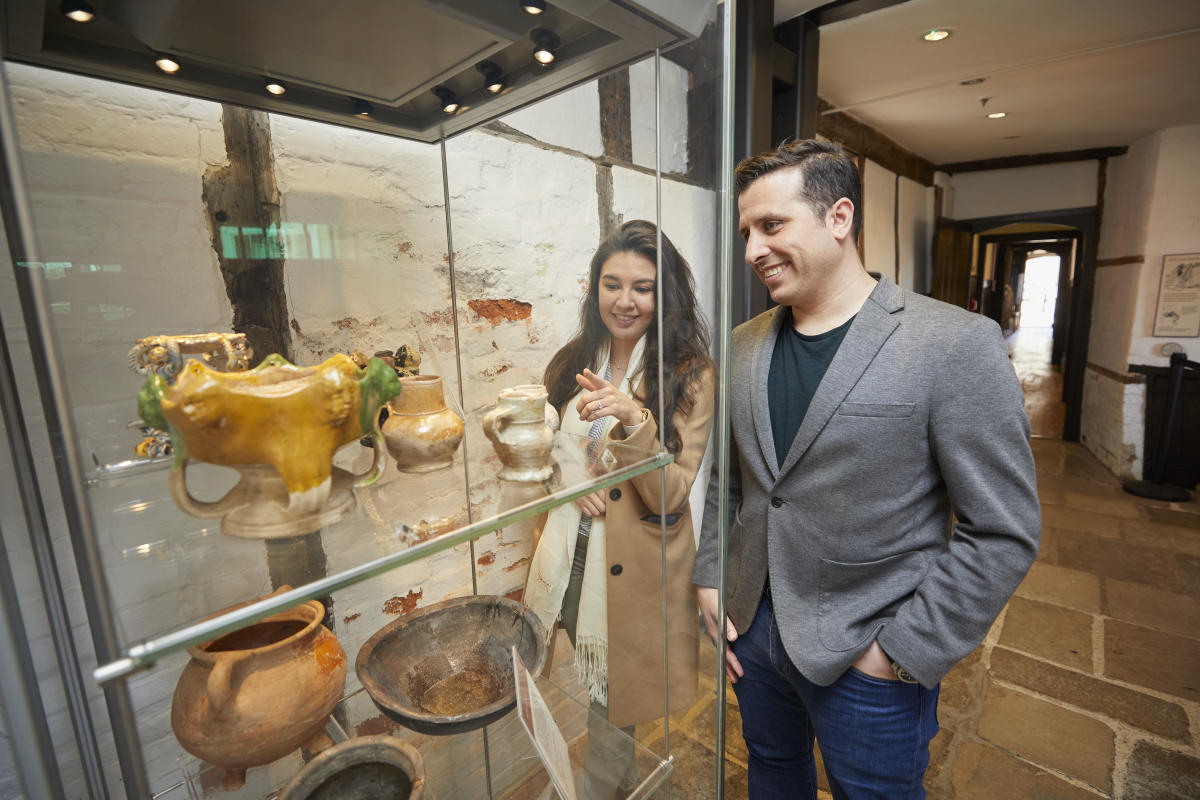 Middle aged couple looking at artifacts in glass cabinet inside Tudor House & Garden