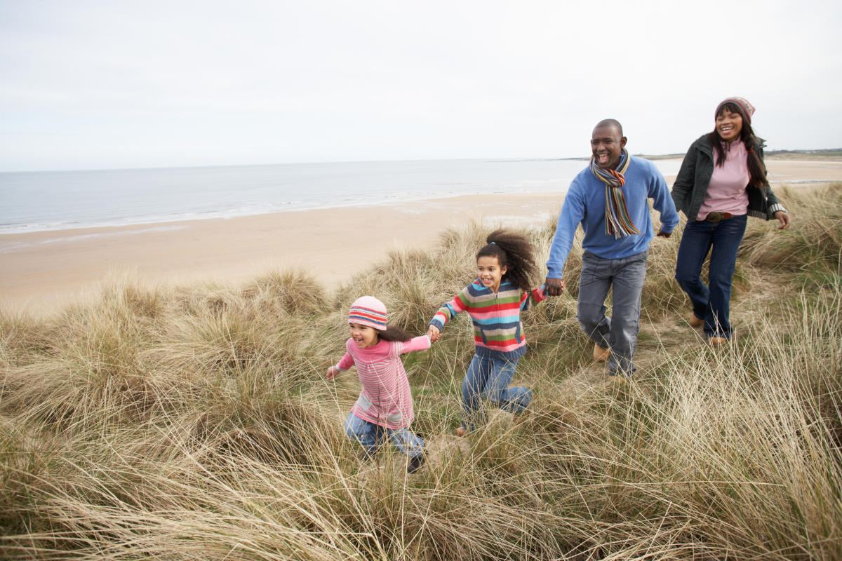 Family running on the dunes by the beach