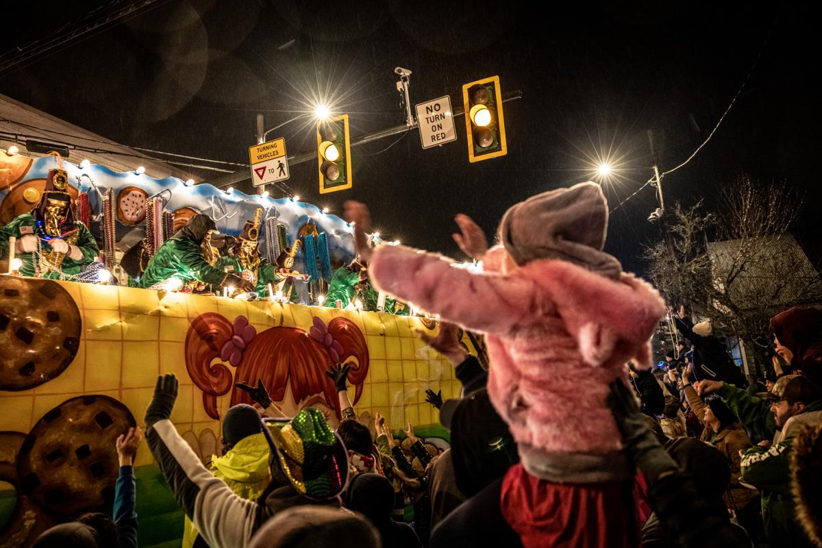 A small child rides the shoulders of their parent so they can catch throws from the floats at Mandeville's Krewe of Eve parade.