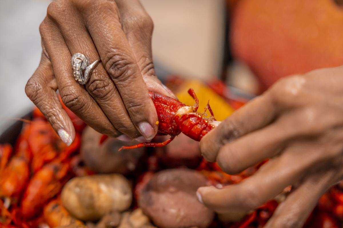 Hands pull apart a boiled crawfish at Mandeville Seafood.