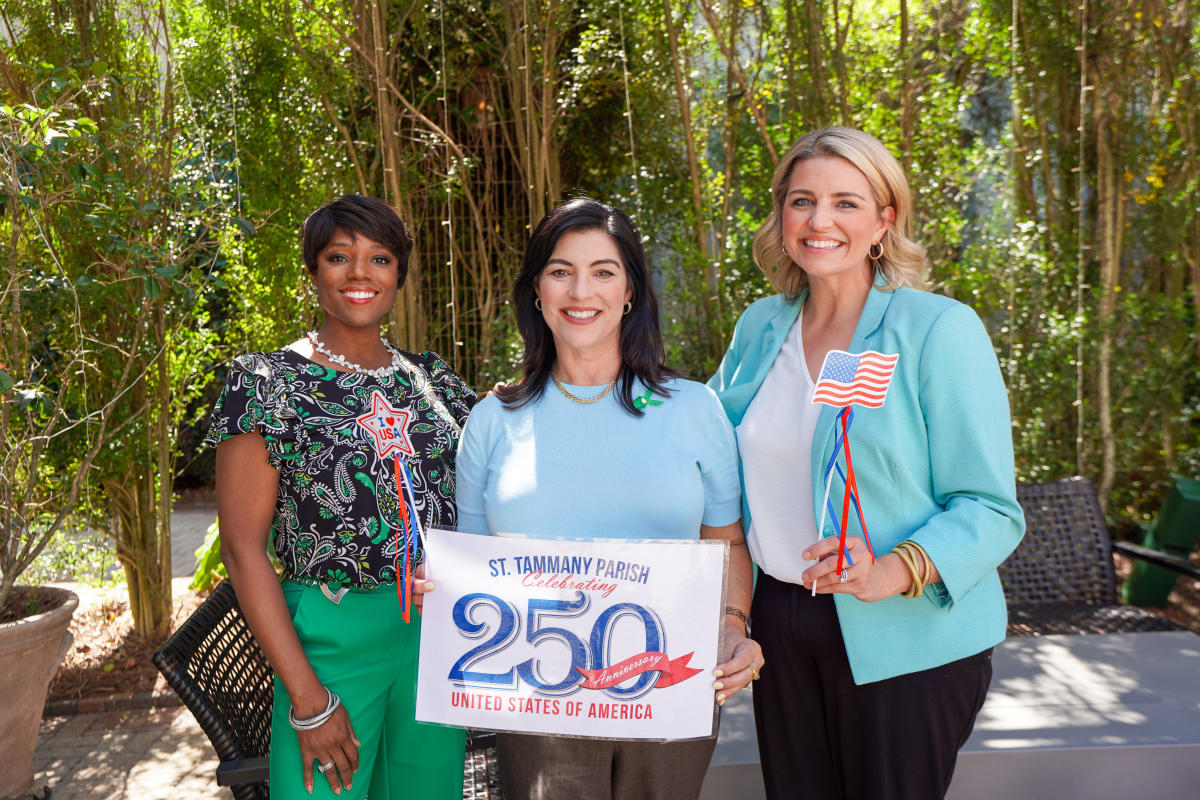 All The Waves hosts Zondra White Jones and Katie Guasco pose with Amy Ybarzabal, who holds a sign commemorating the 250th anniversary of the United States.
