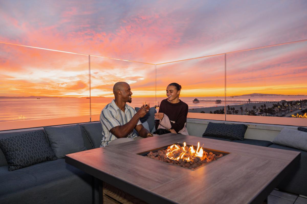 Couple cheerings at Offshore 9 Rooftop Lounge with the sunset in the background