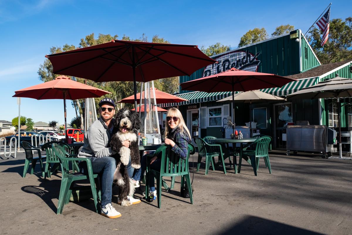A couple with their dog sitting outside at the Park Bench Café in Huntington Beach