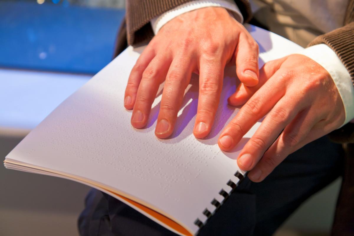 Man reading a braille information pack