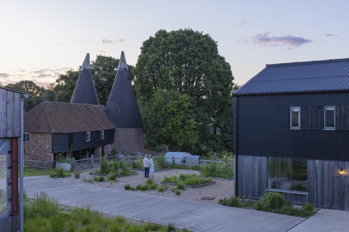 A couple stand in the courtyard between the barn buildings at Tillingham in Sussex