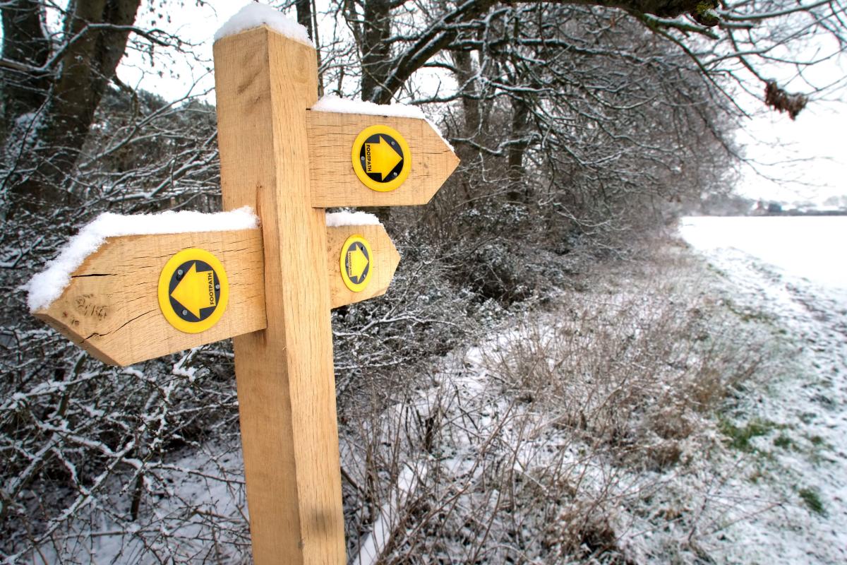 A public footpath waymarker with three arrows in Sussex