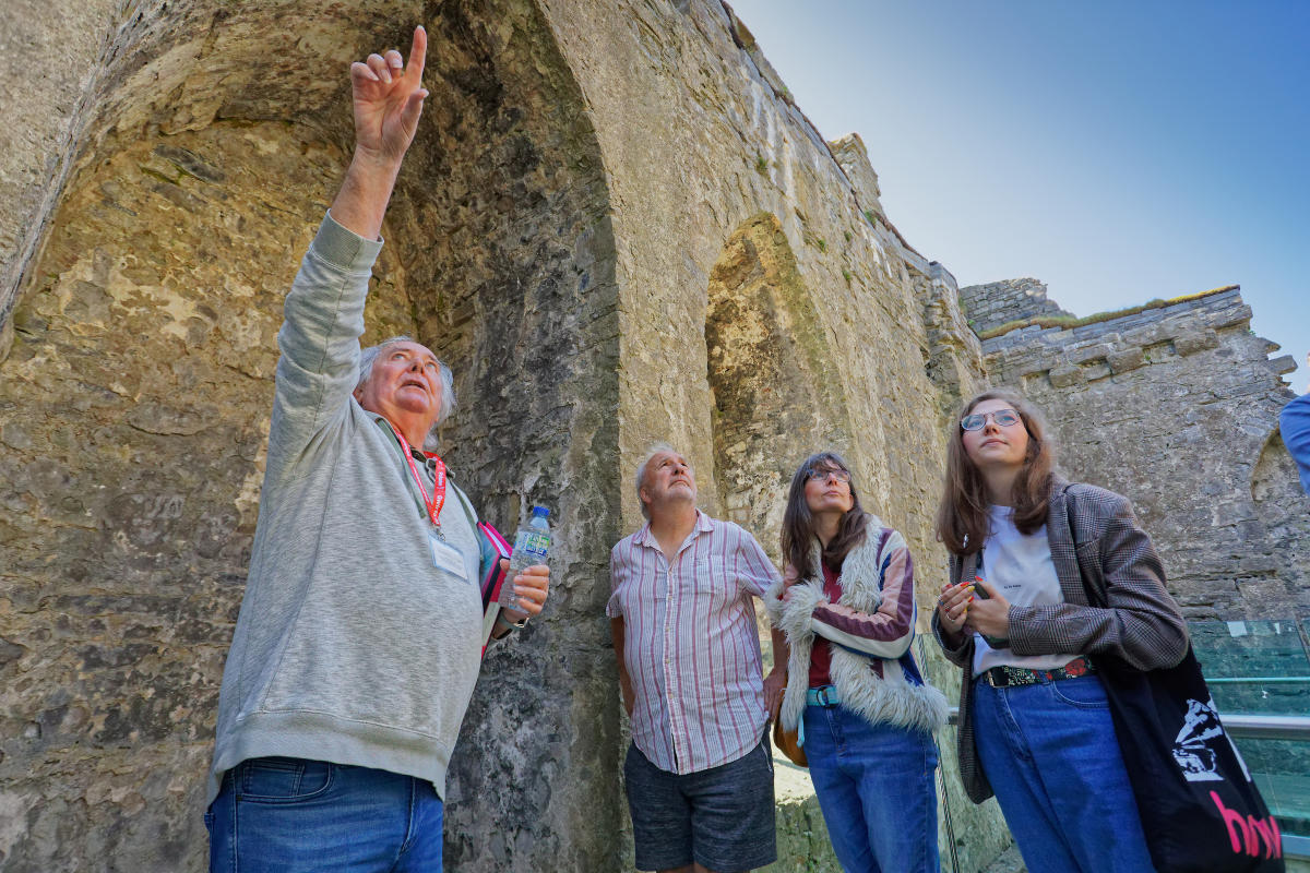 Oystermouth Castle tour guide pointing out something to three people.