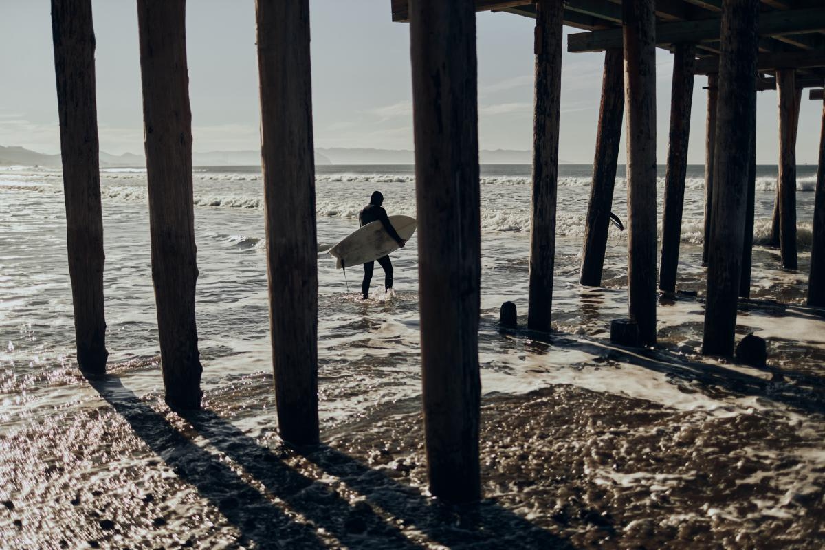 View of Aaron Jackson surfing from under Cayucos Pier.