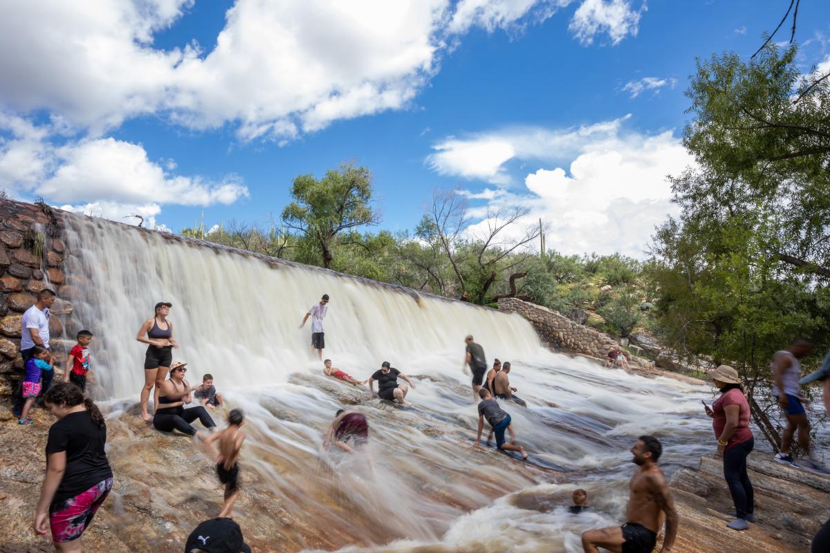 People cooling off under a water fall in Sabino Canyon