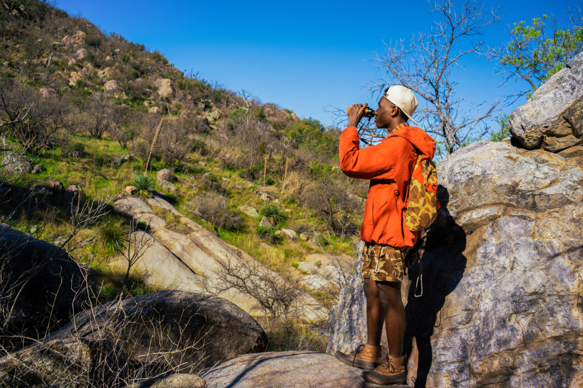 Man standing on rock looking out to lush greenery in Madera Canyon