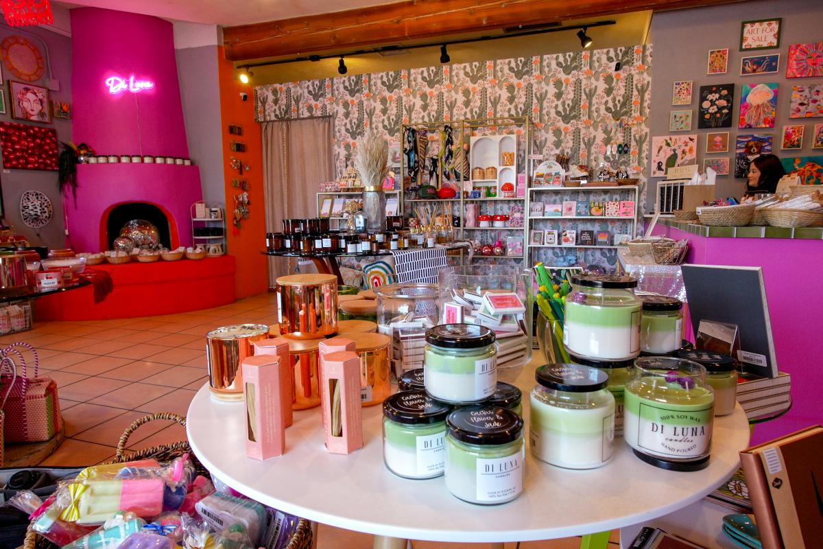 inside of a brightly colored store, Di Luna Candle Shop, with shelves of candles, ceramics, cards, and other local goods