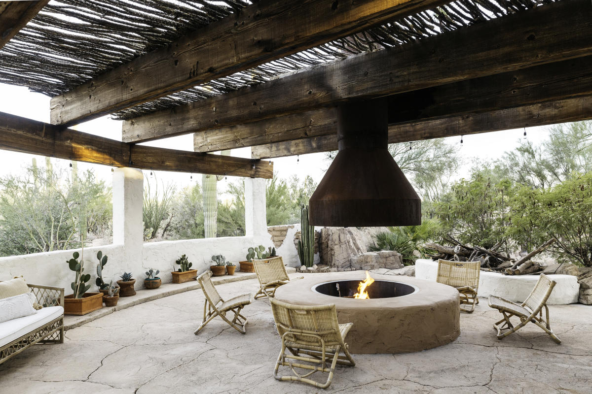 Five Ratan chairs sitting around an outdoor fireplace on The Joshua Tree House patio