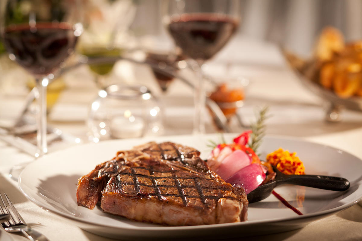 close up photo of a steak on a plate with some onions and floral garish at PY Steakhouse