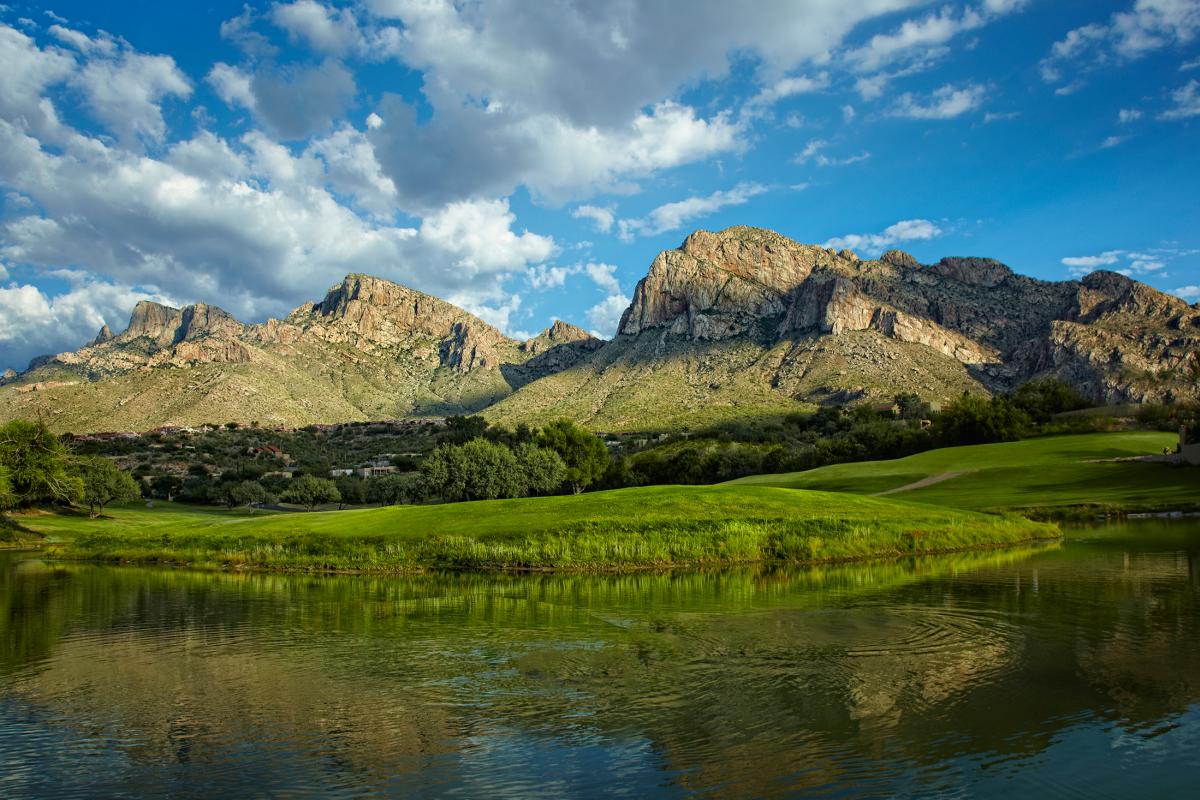 landscape of a mountain scene with a large pond and green grass