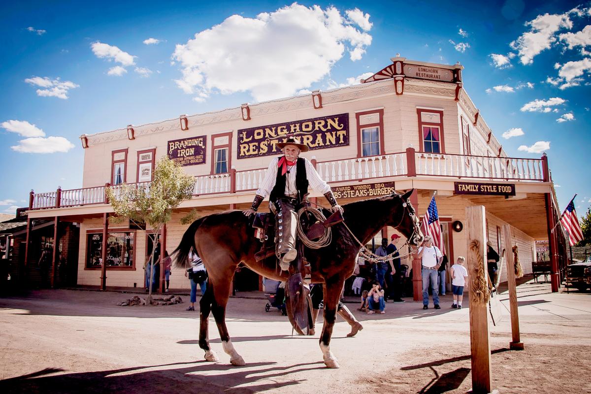 cowboy on a horse in front of an old western building with a sign that says "Longhorn restaurant"