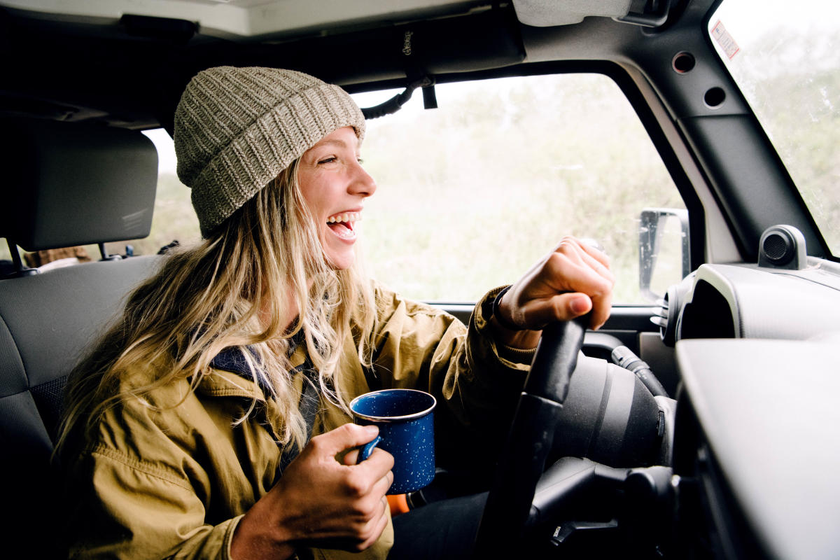 Woman laughing while driving and holding a cup