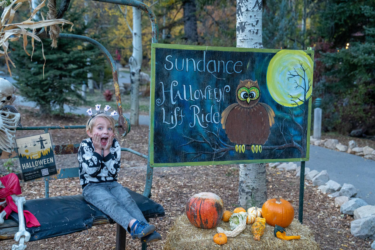 child sitting next to Halloween Lift Ride sign