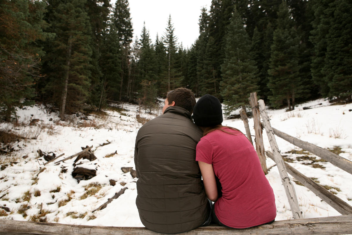 Couple sitting on log in snowy scene