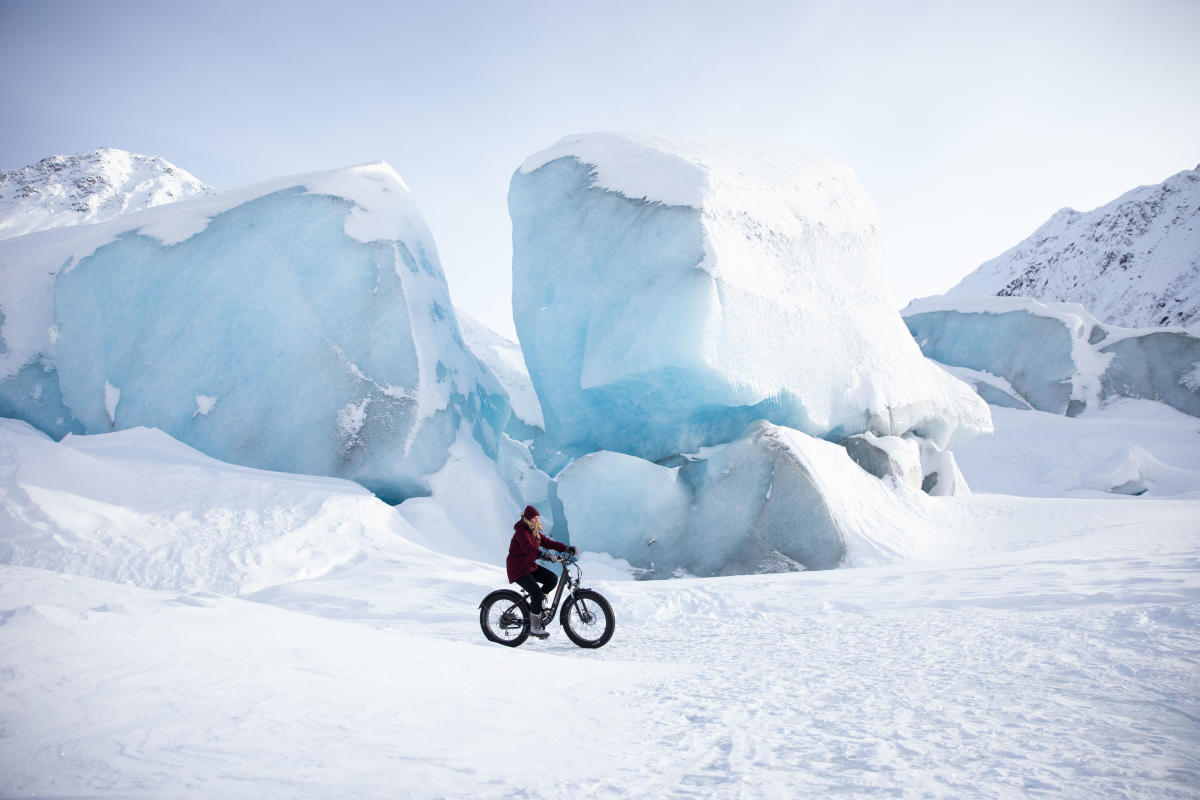 a woman rides a fat-tire bike on a frozen glacier lake