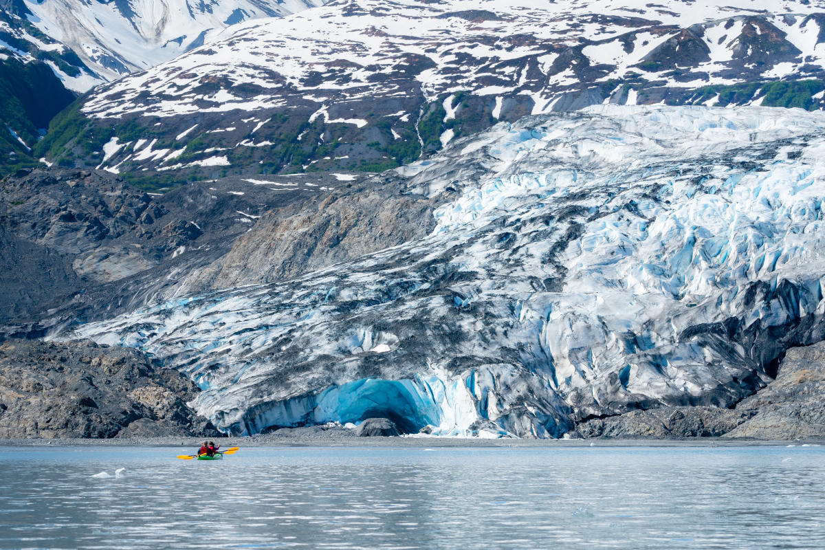 a kayaker paddling in front of a tidewater glacier